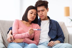 couple looking confused at a pregnancy test